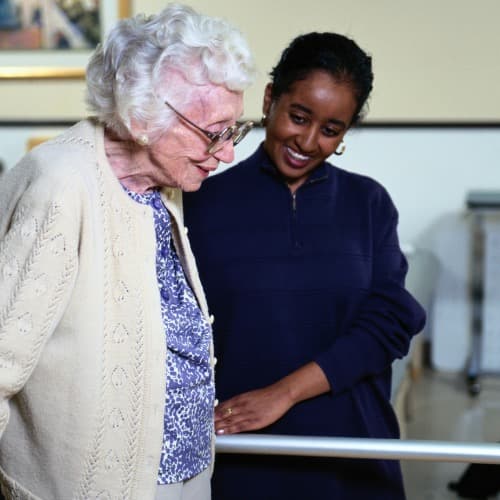 Adjo, certified home care aide, warmly assisting an elderly client in their home